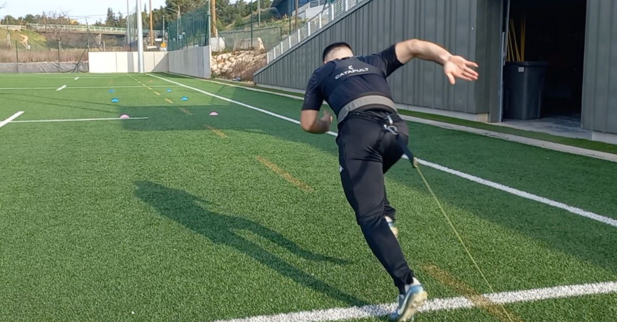 A man in athletic clothing sprints on artificial turf